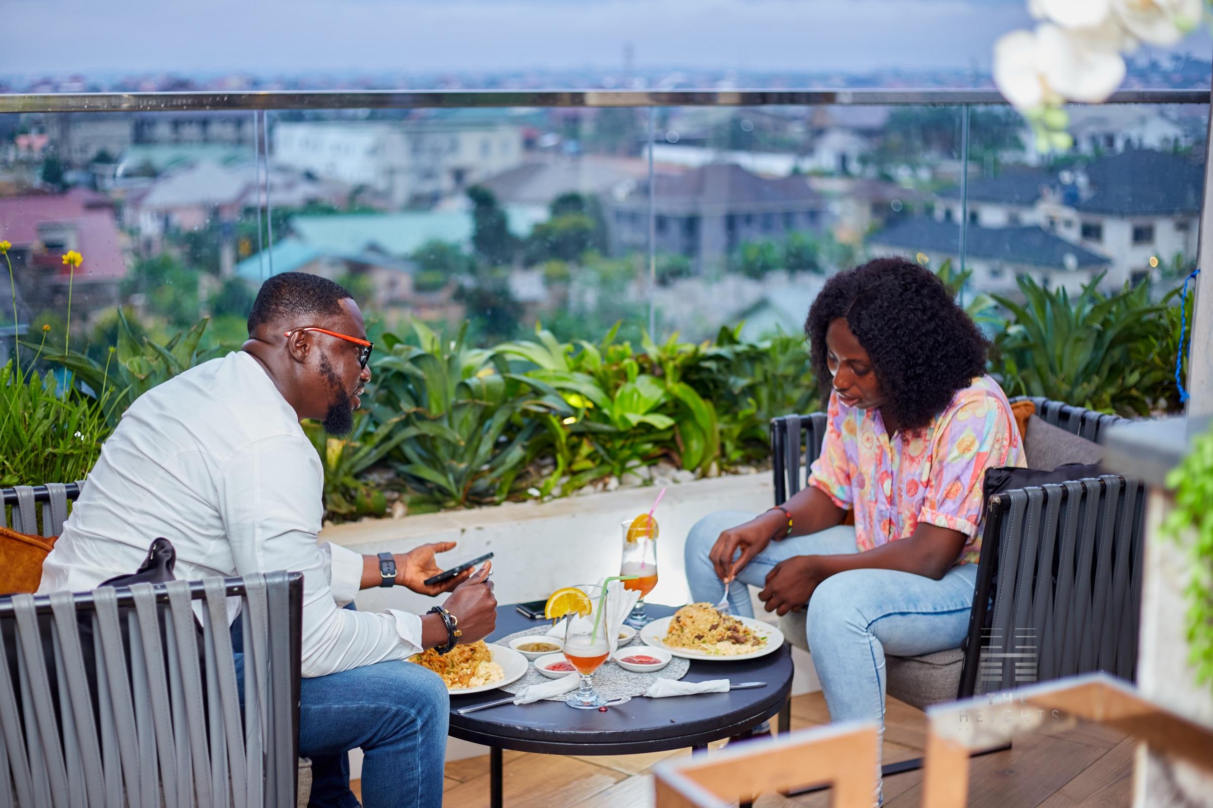Two guests dining on The Heights rooftop terrace with a view over Kumasi